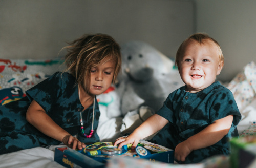 Two children playing on a bed with toys