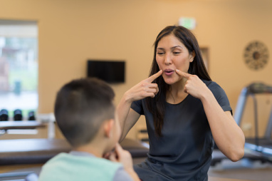 A speech and language therapist works with a young boy