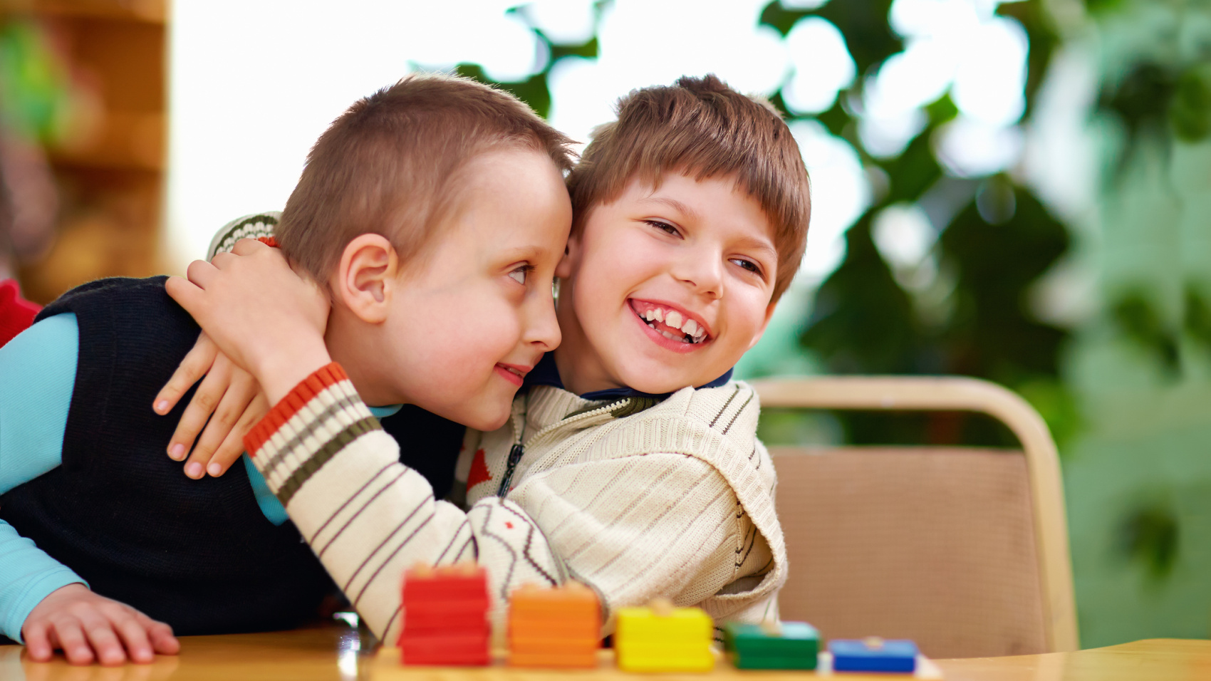 Two disabled young boys smiling hugging each other