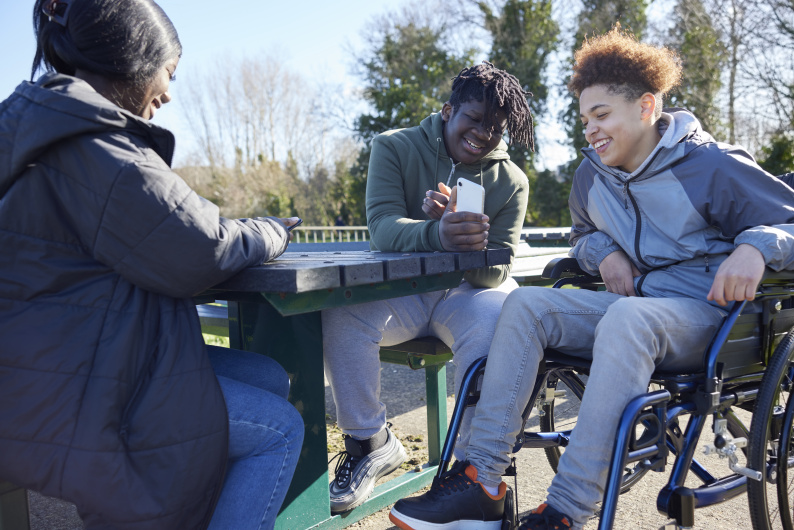 Three teenagers sat outside sharing a joke