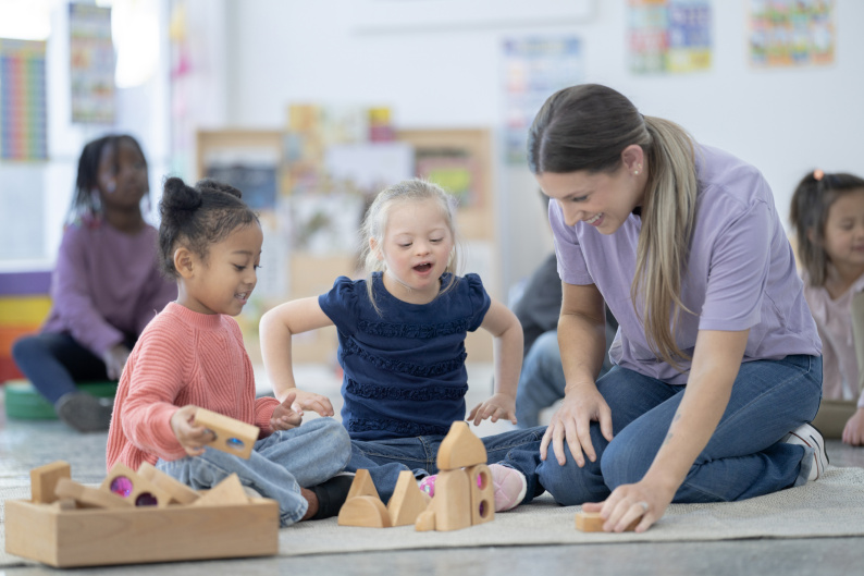 Nursery worker interacting with two young girls 