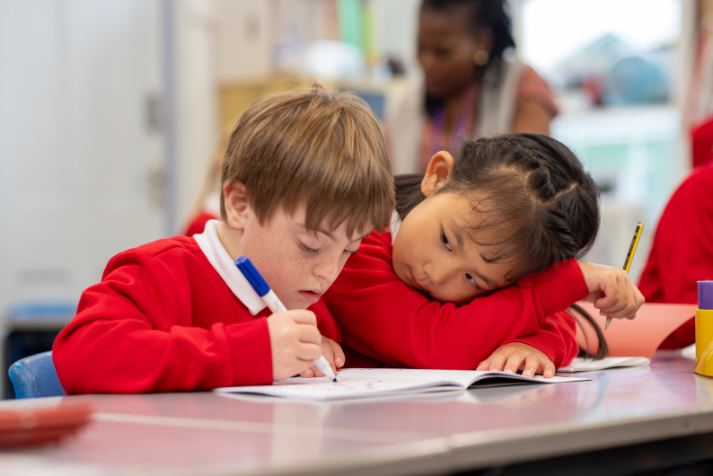 Boy with Downs Syndrome working alongside a girl in a school classroom